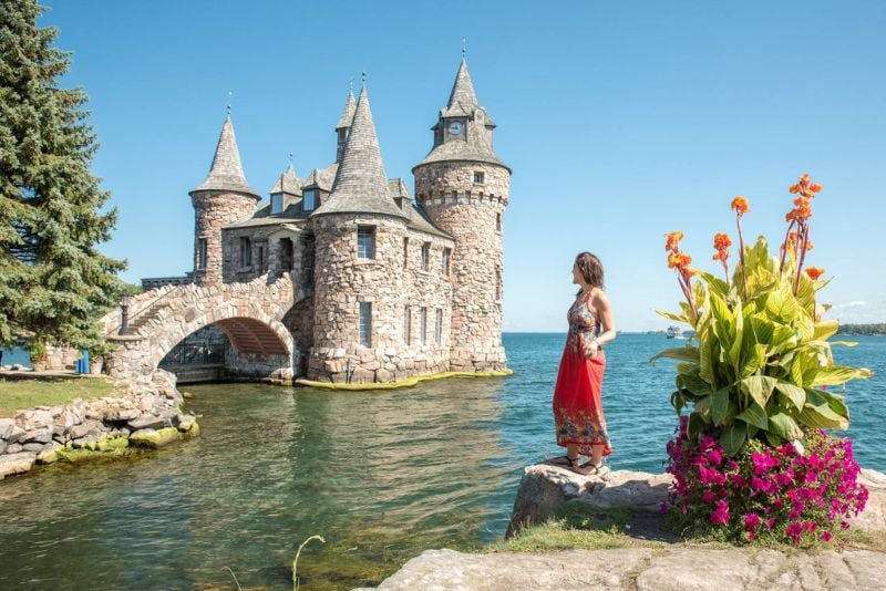 一名女子在从纽约出发的公路旅行中，在1000群岛的博尔特城堡前拍照留念