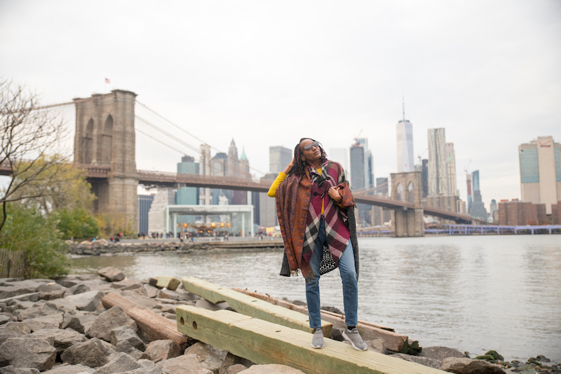 在一次纽约建筑之旅中，一名女子在DUMBO中曼哈顿天际线前摆姿势